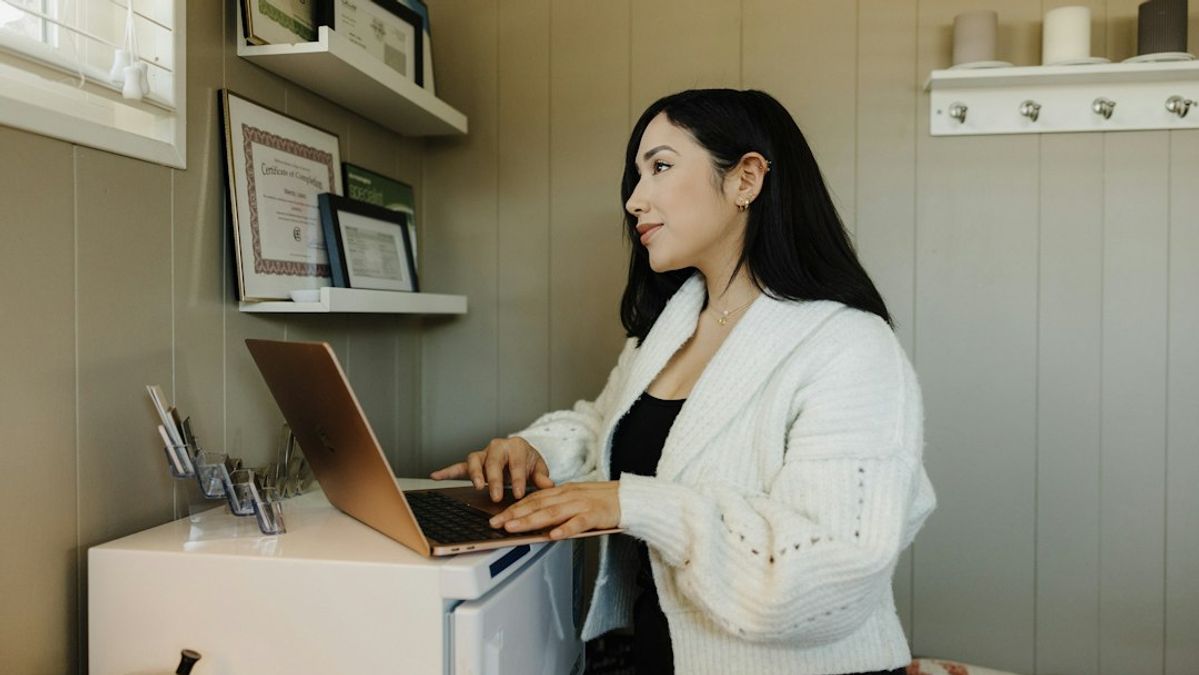 a woman sitting at a desk using a laptop computer