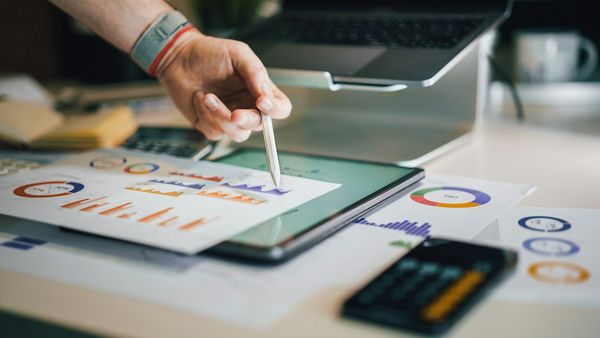 person using stylus on tablet with charts