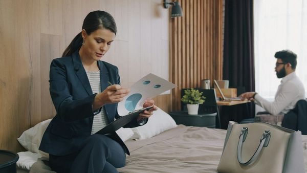 A woman in a suit reviewing charts on a bed in a hotel room