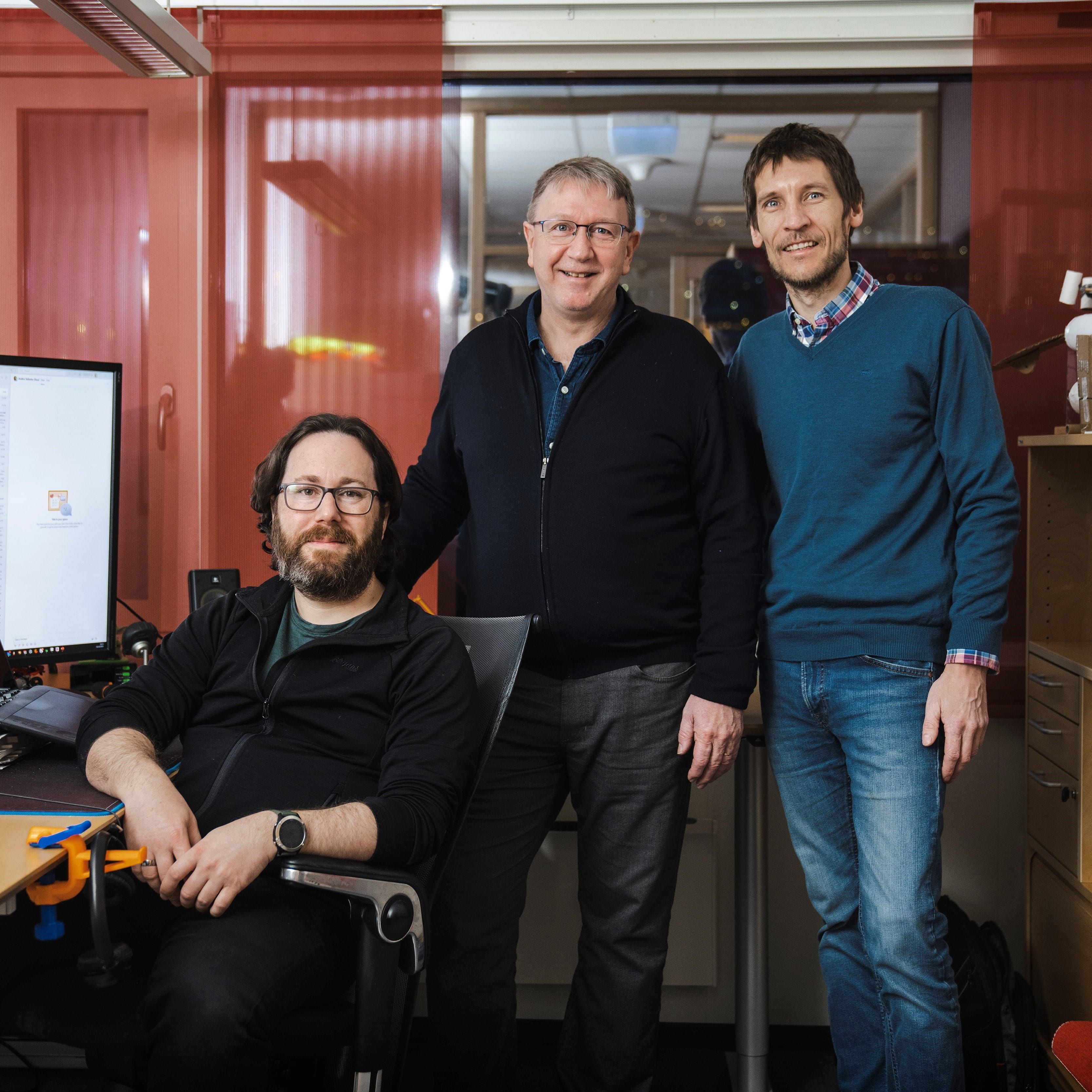 Three men by a desk with a illustration showing on the computer