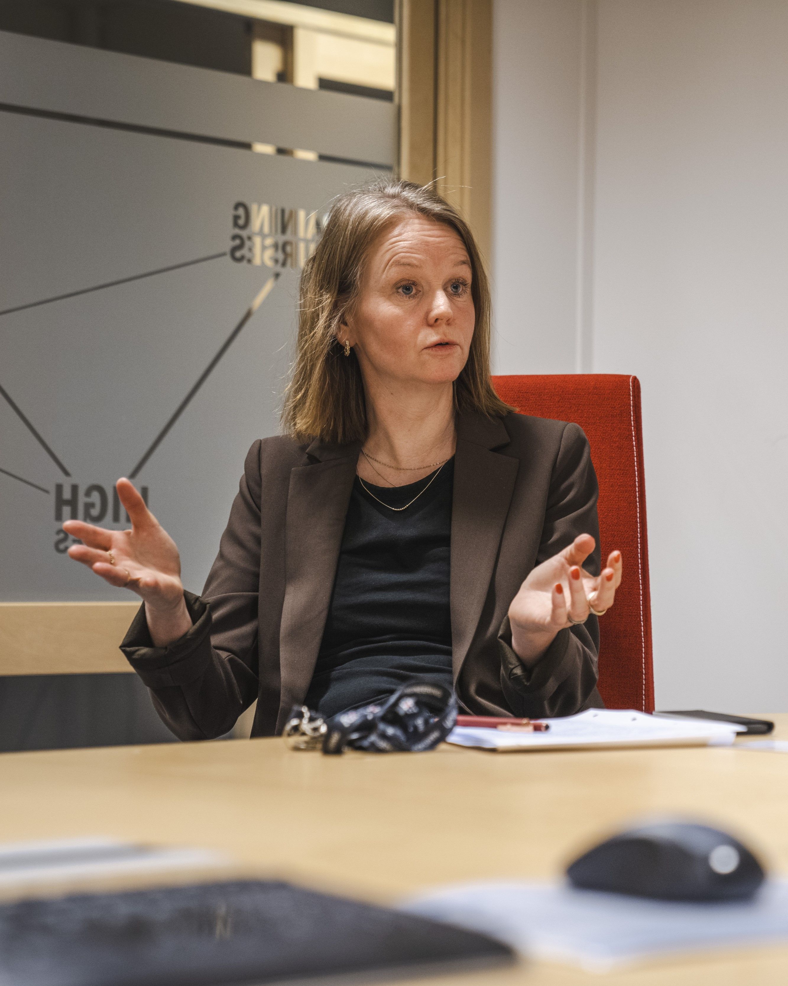 Anne Mathilde sitting by a desk talking about AXTechs new office in Tønsberg