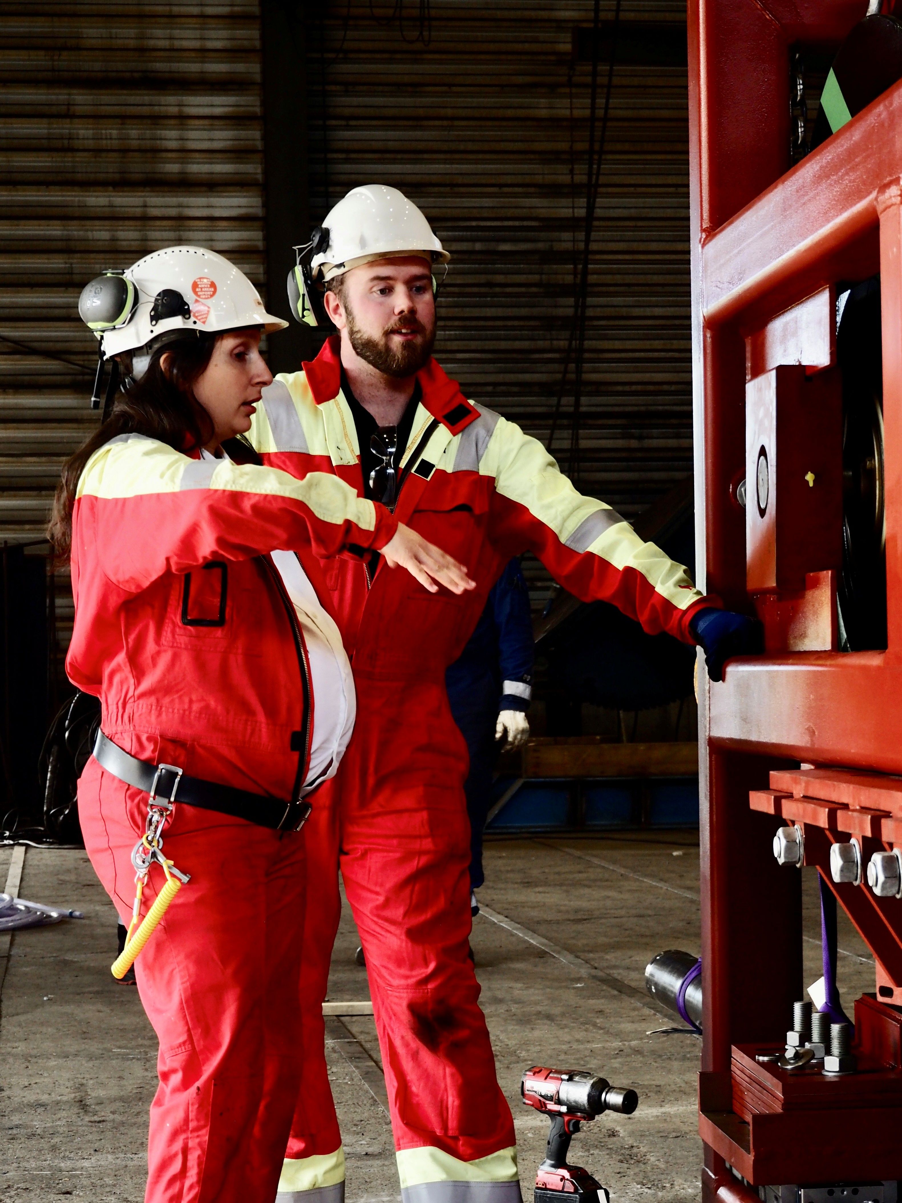 Pregnant woman and man in overalls working