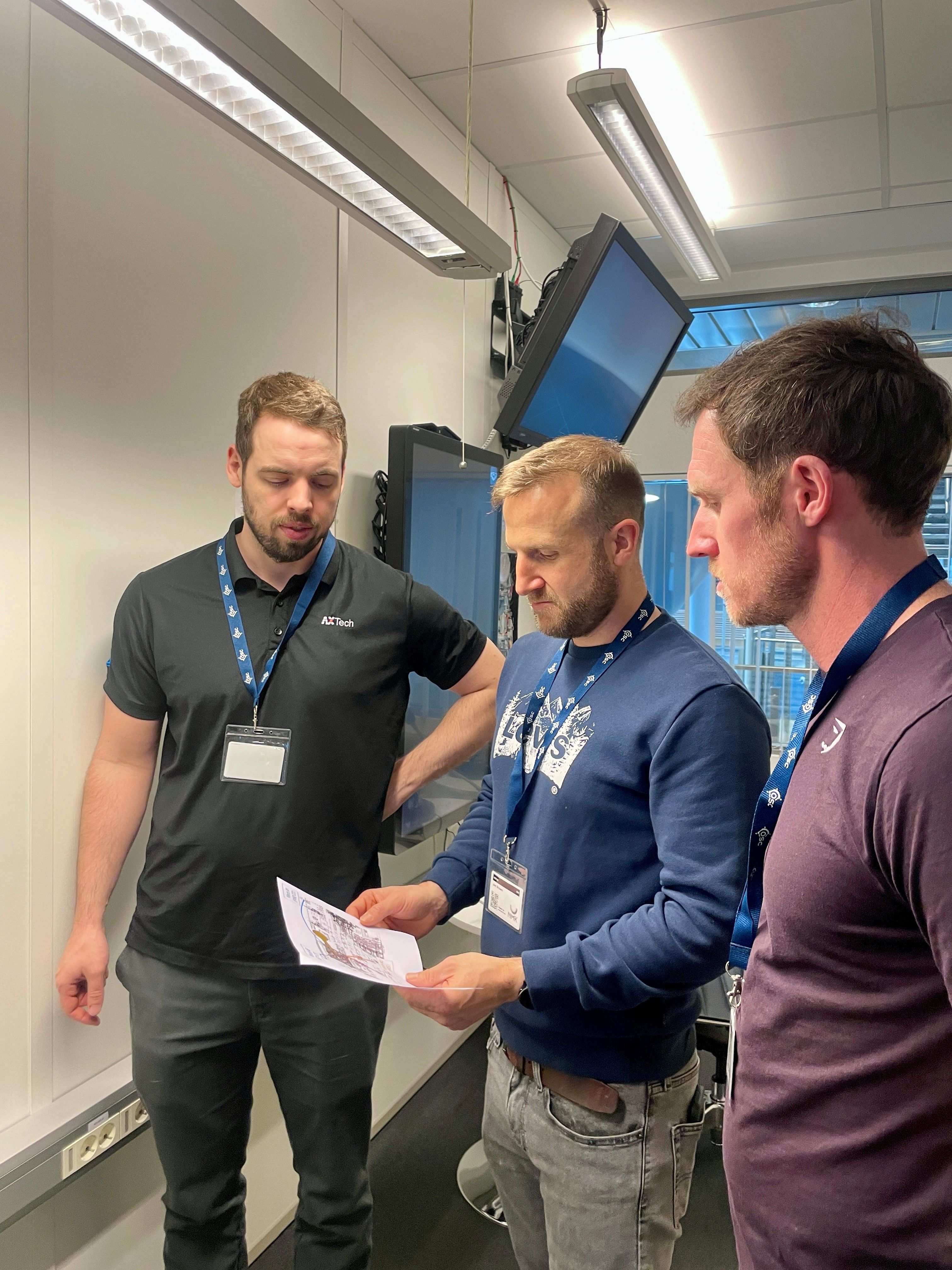 Three men looking at a paper
