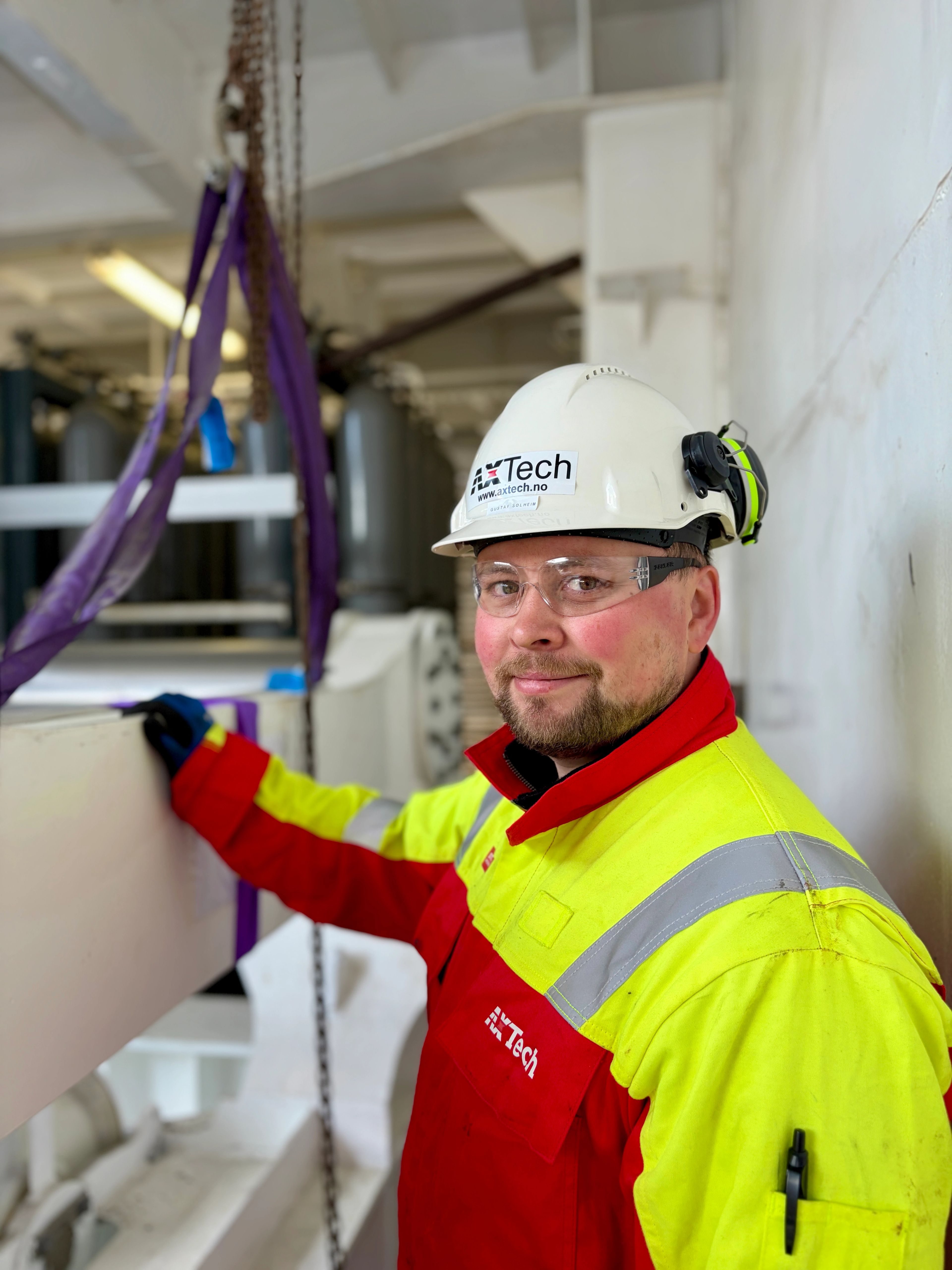 Man named Gustav in overalls and helmet leaning on a winch systrem