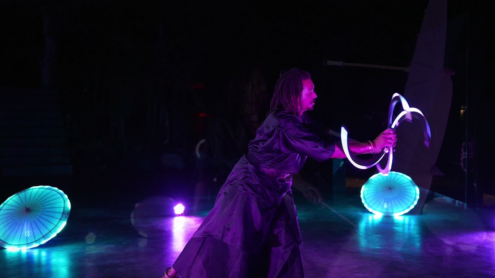 JeanSou jongle avec des anneaux lumineux sur scène