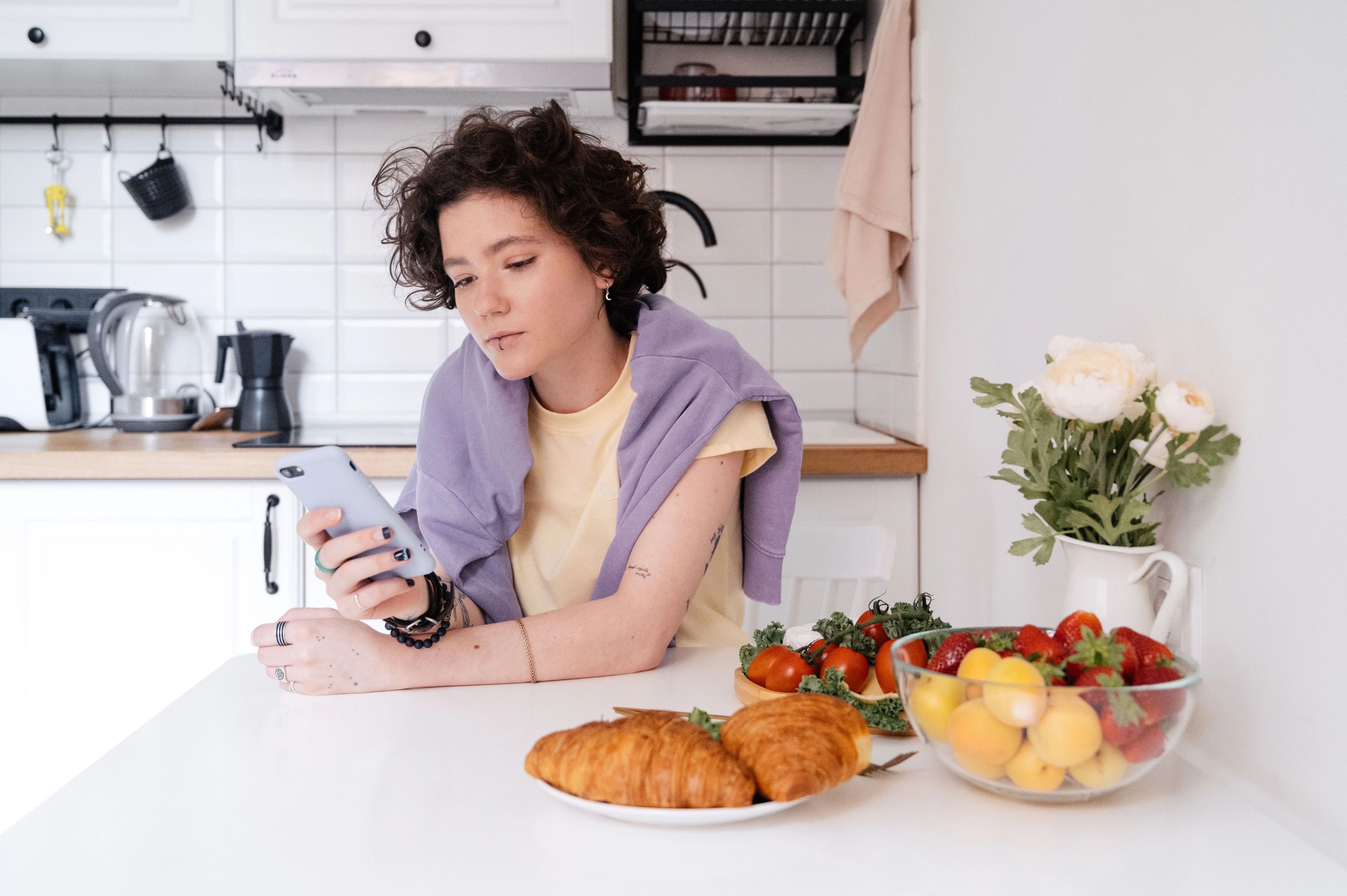 Young woman lookint at her phone over a small breakfast