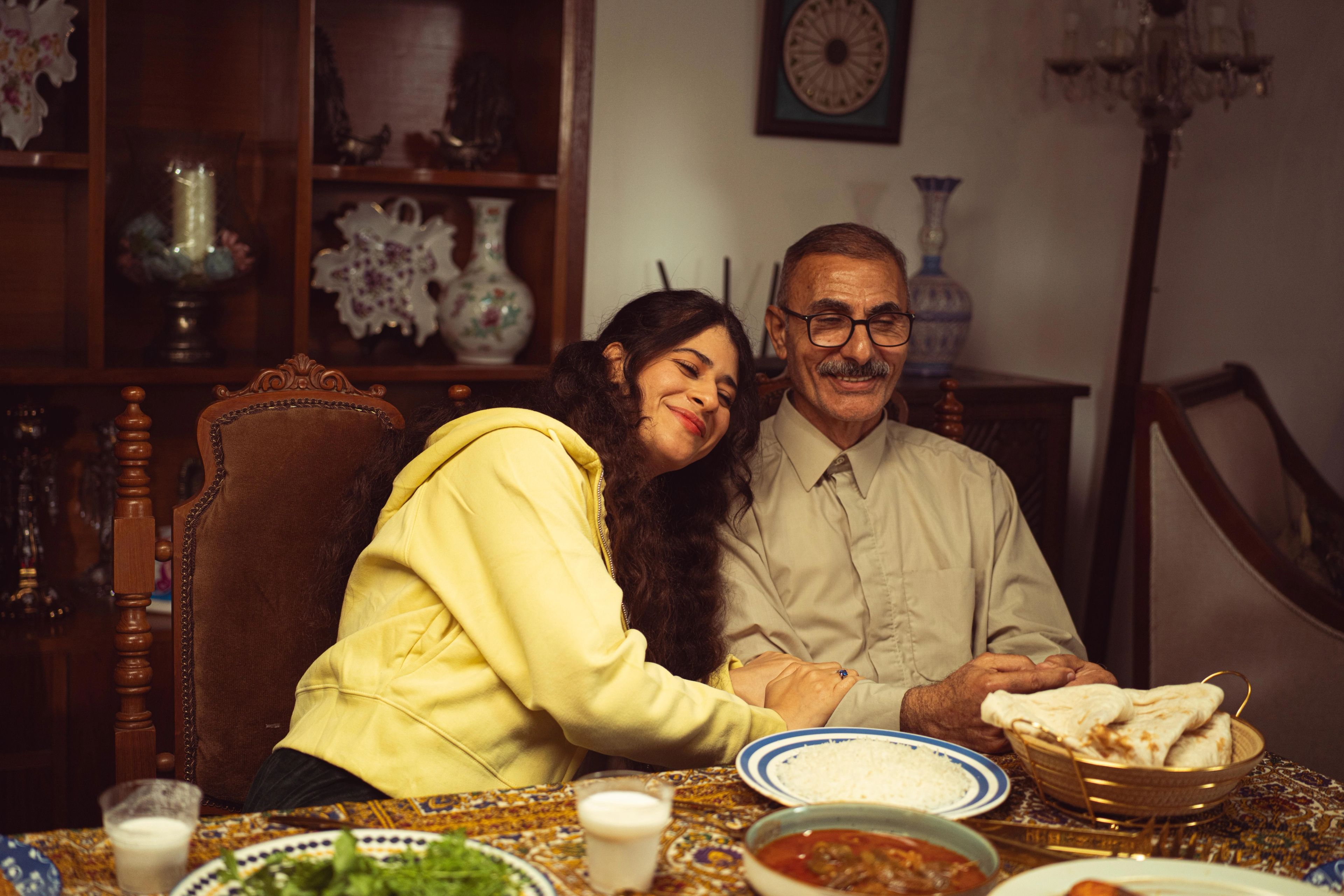 Father and daughter sitting by each other at family dinner table