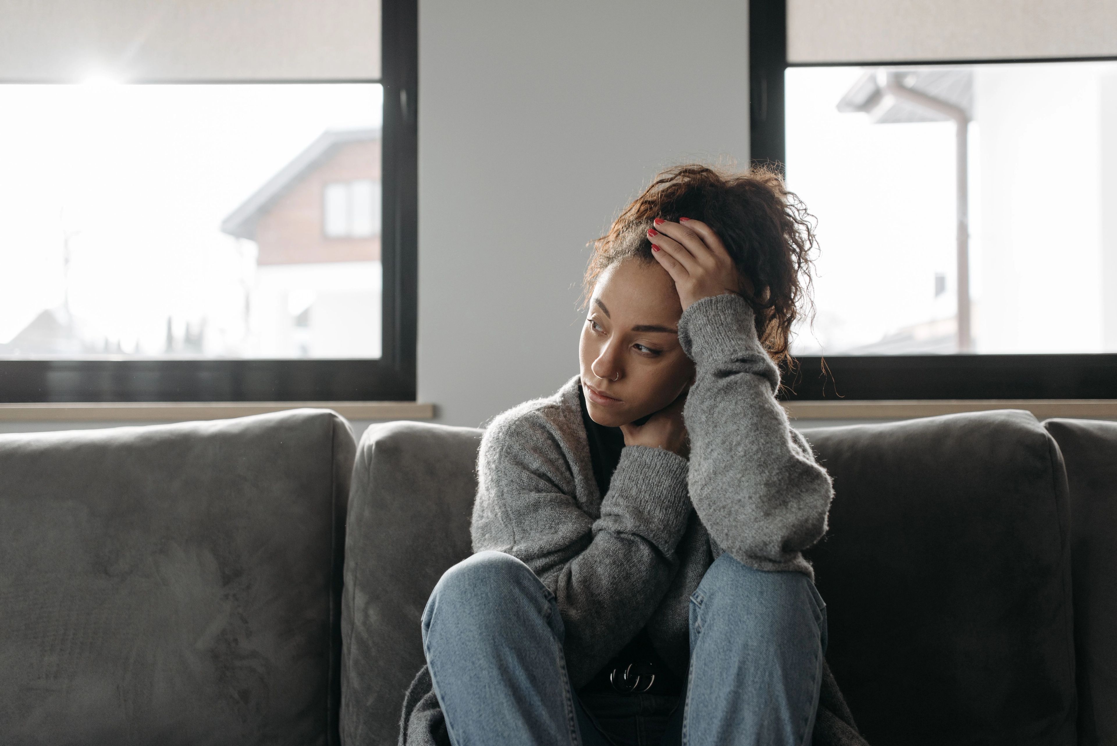 A young woman sitting on a couch, looking distressed