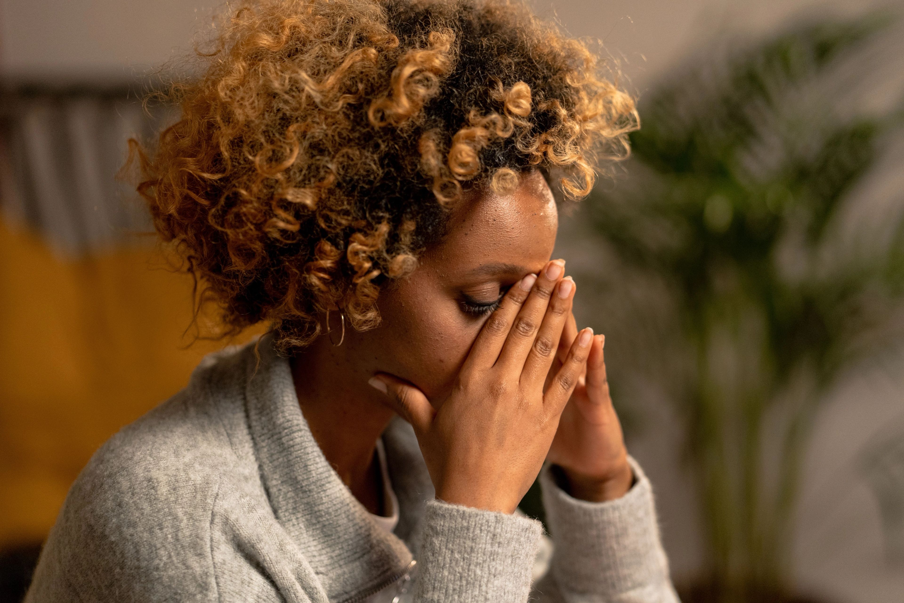 A young woman with her head in her hands, looking distressed