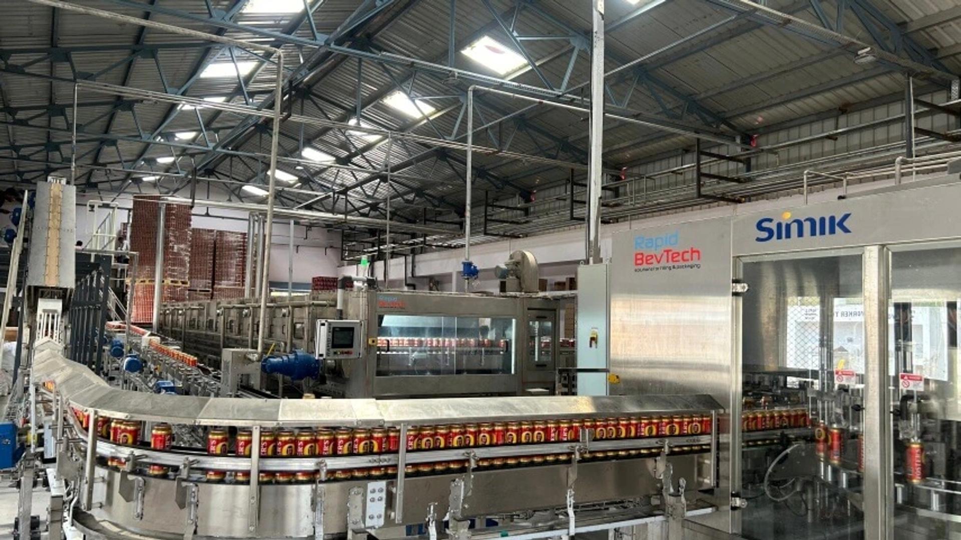 Latas de Foster's en la línea de llenado de Rapid BevTech con bloque llenadora-cerradora Simik
