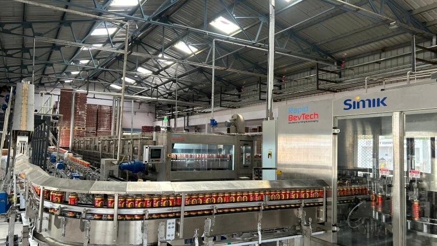 Latas de Foster's en la línea de llenado de Rapid BevTech con bloque llenadora-cerradora Simik