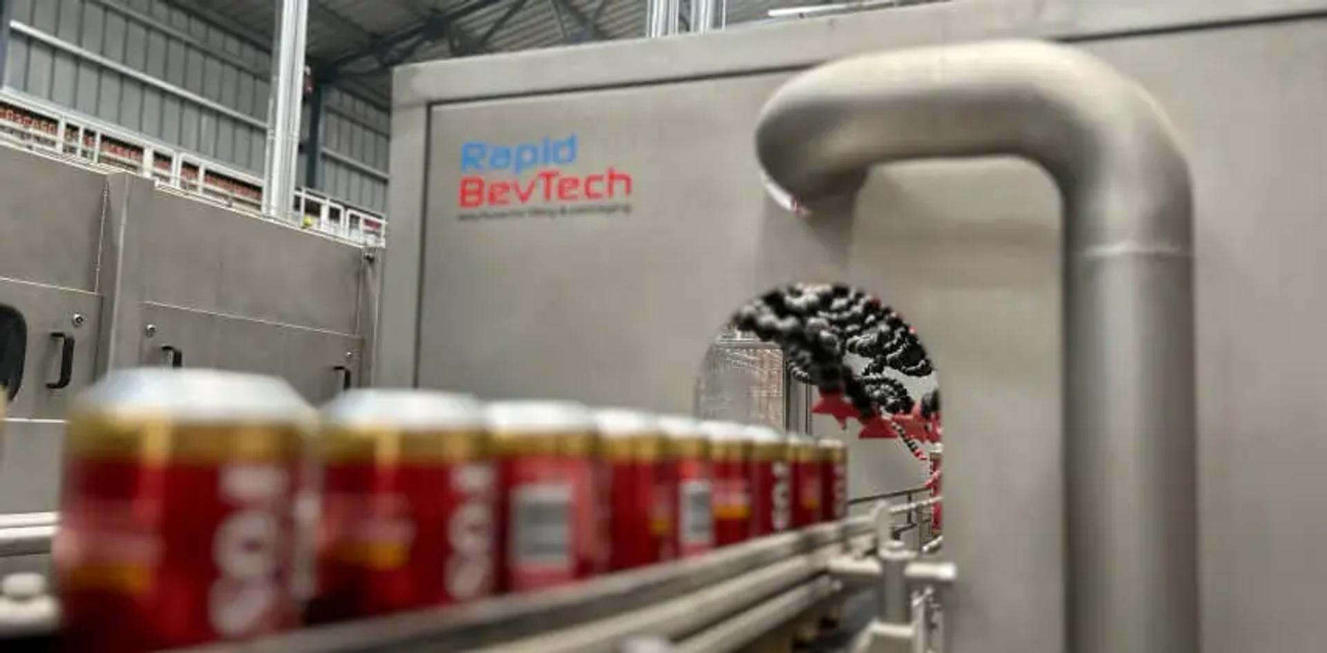 Latas de Foster's en el transportador con la marca Rapid BevTech