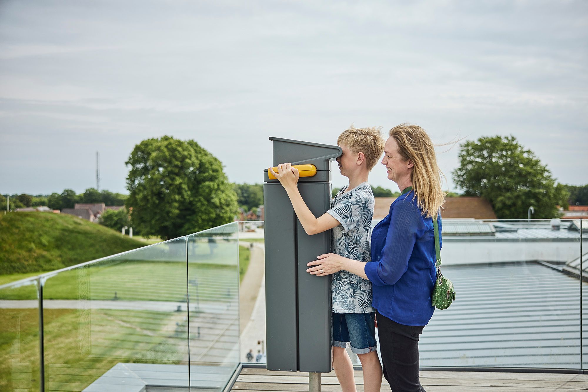 Mother and son looking through binoculars on the roof