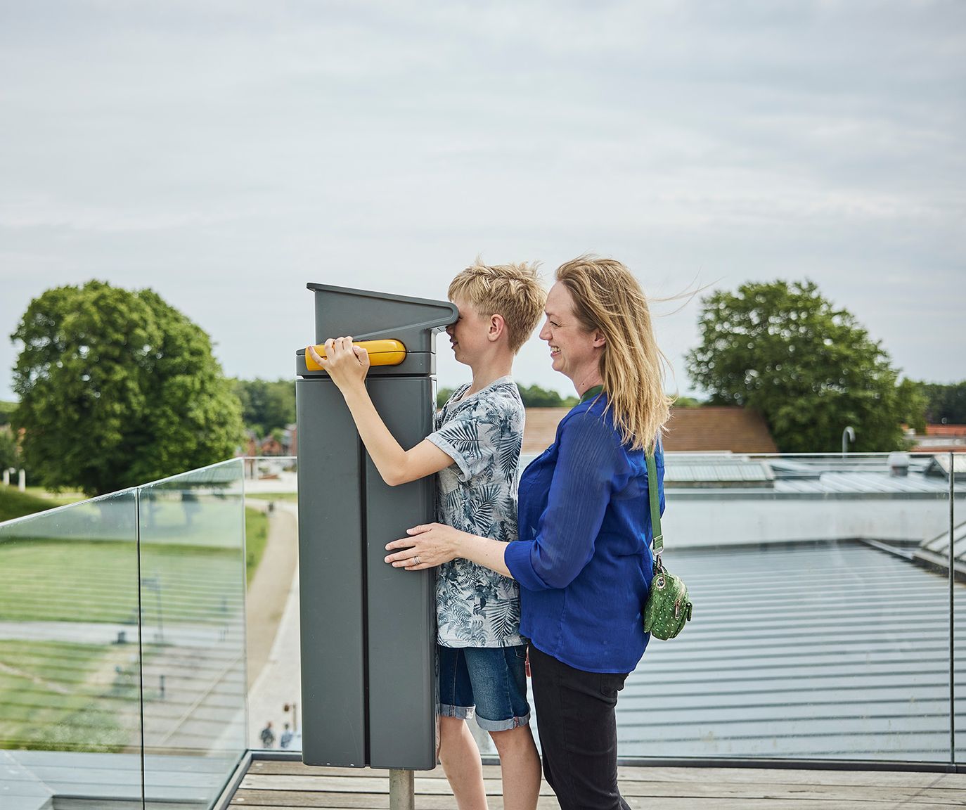 Mor og søn kigger i kikkert på taget