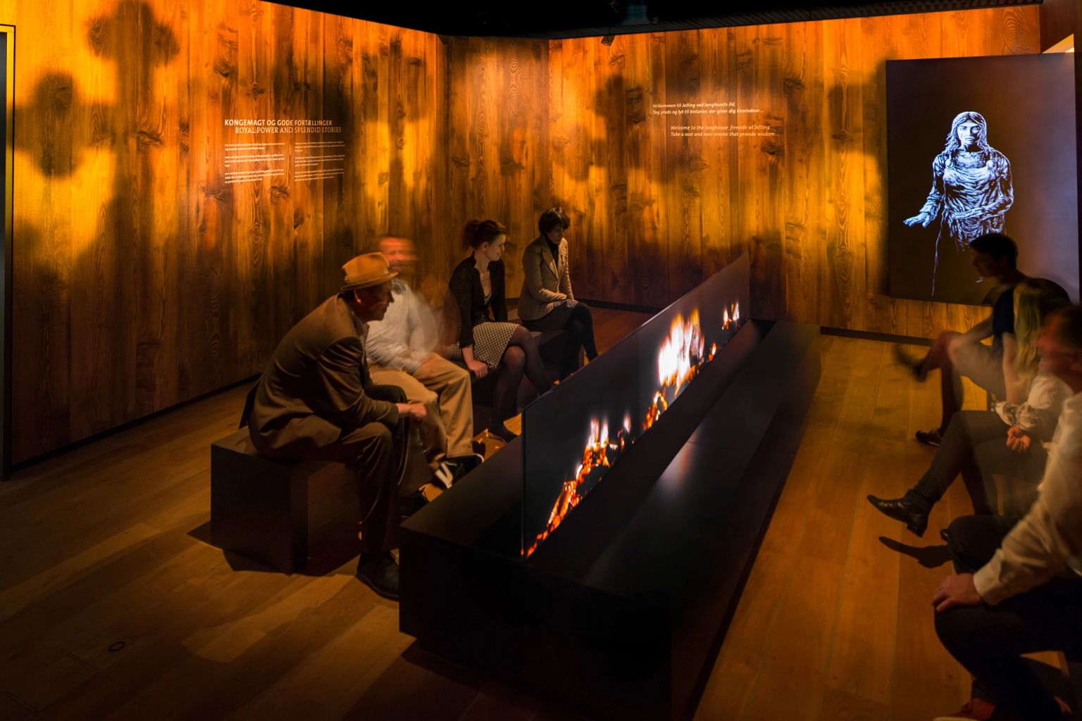 Gæster sidder om et digitalt bål i oplevesescenteret