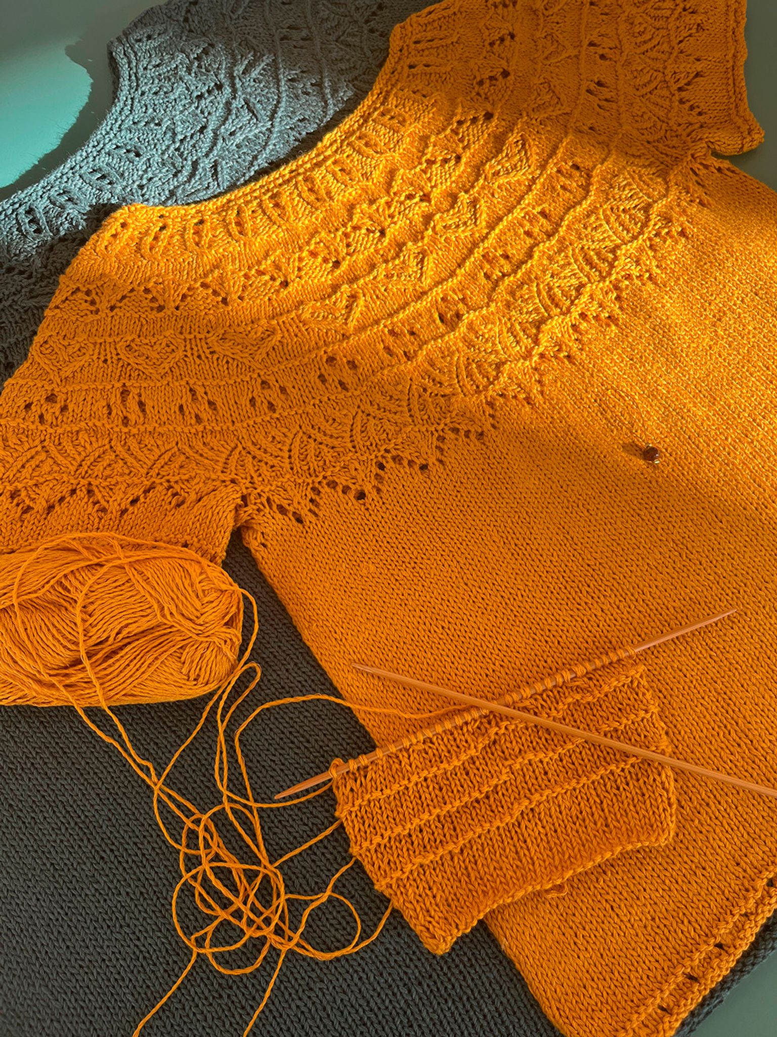 En gul strikket bluse med garnnøgle på