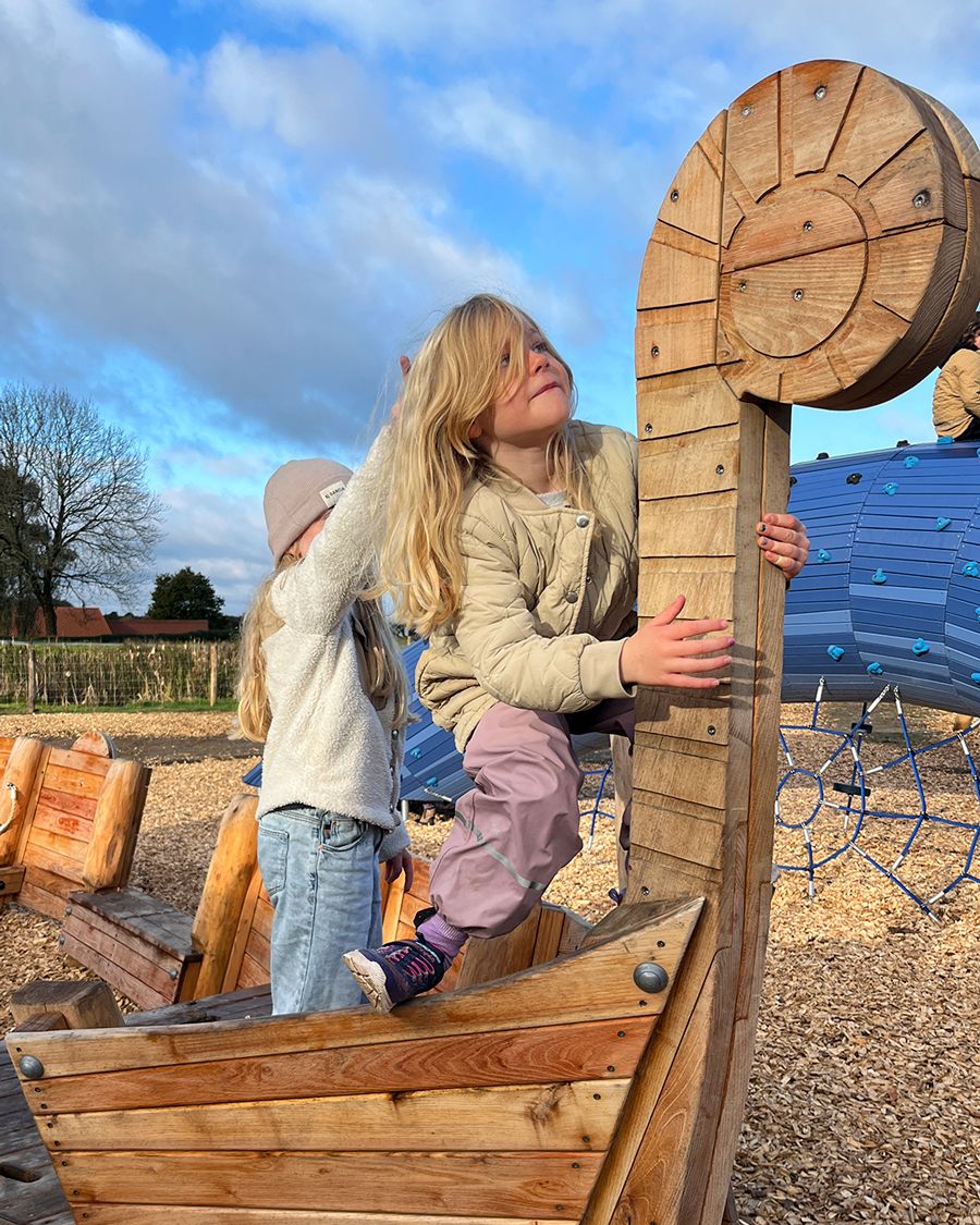Two girls climbing on a miniature ship in a playground
