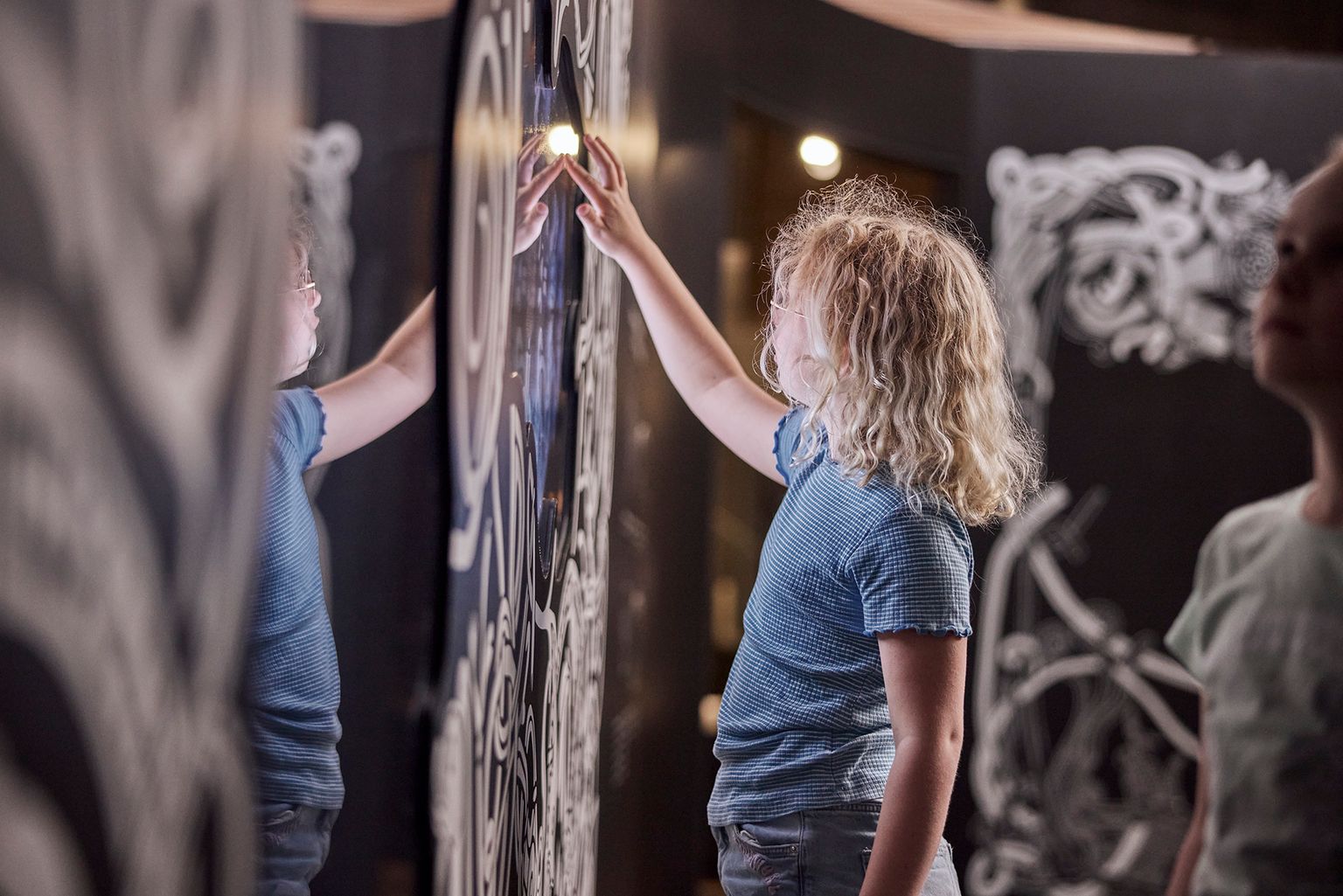 Lille pige rør ved tavle i oplevelsescenteret