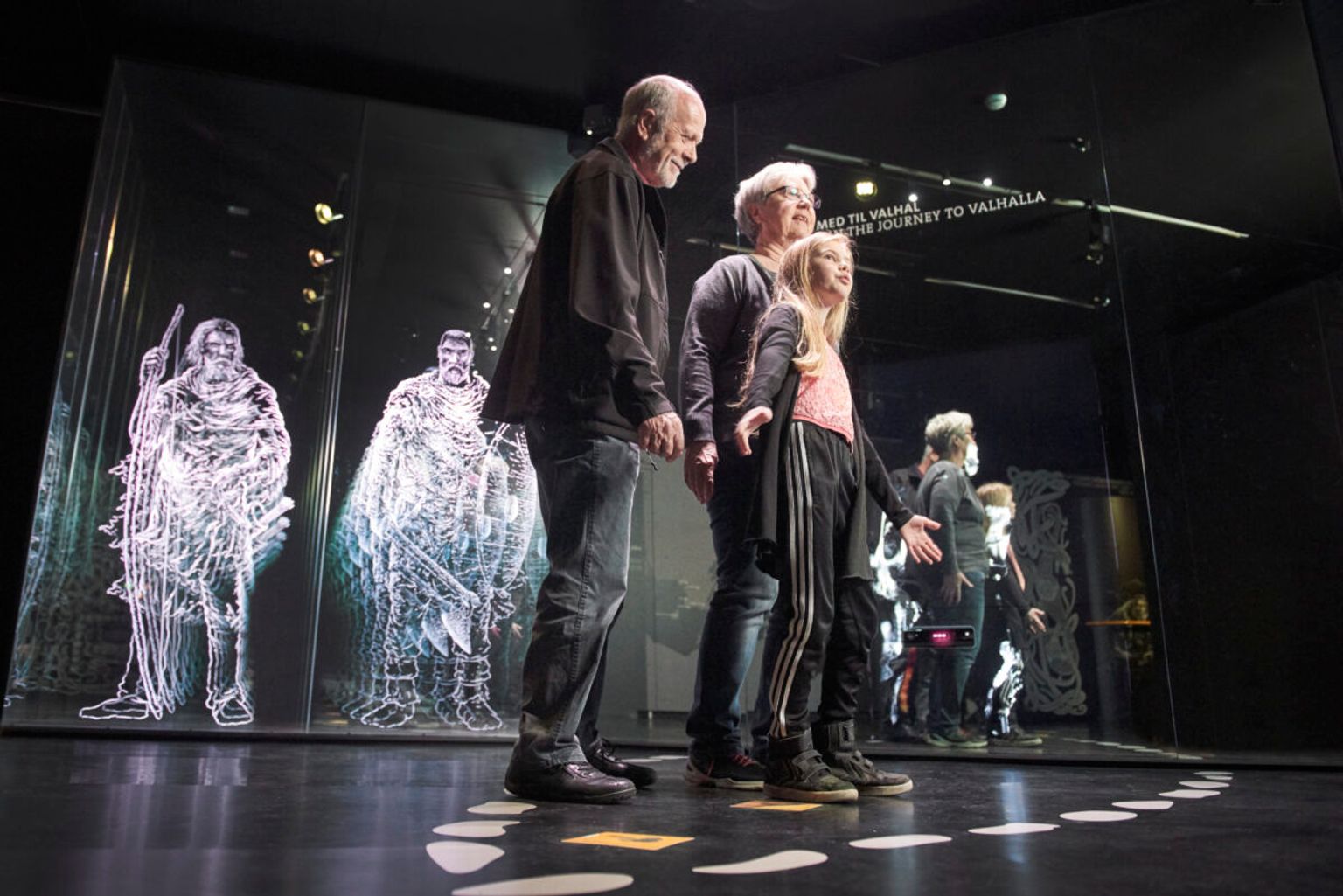 To voksne står med et barn i vikingeudstillingen og kigger rundt på spejlene