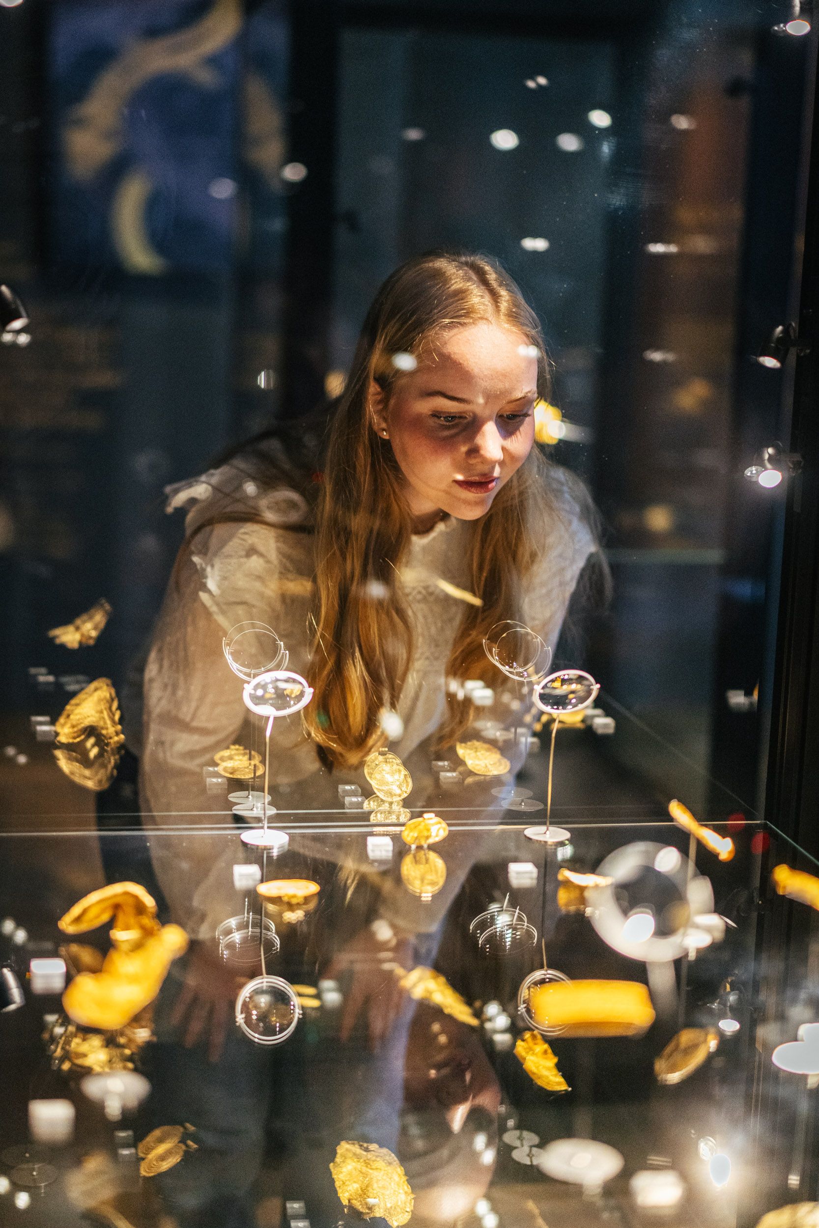 Woman looking at gold treasure in a display case