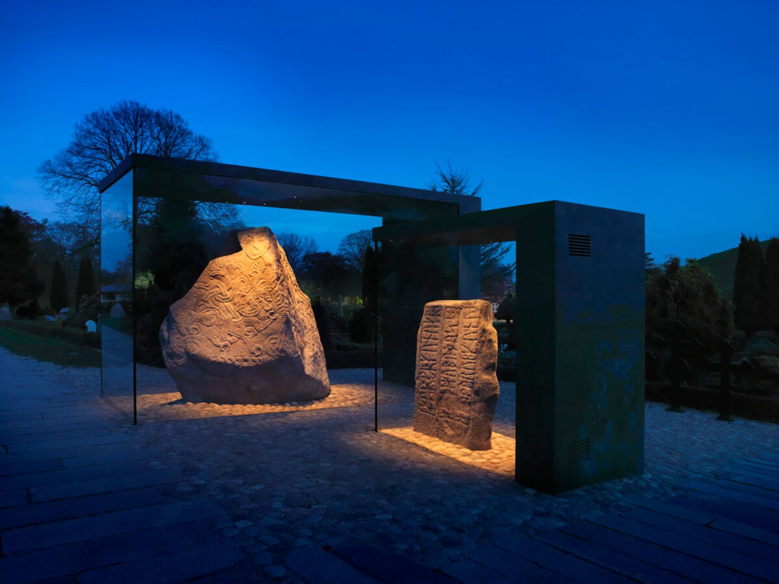 Jellingstenene i montre om aftenen med lys på