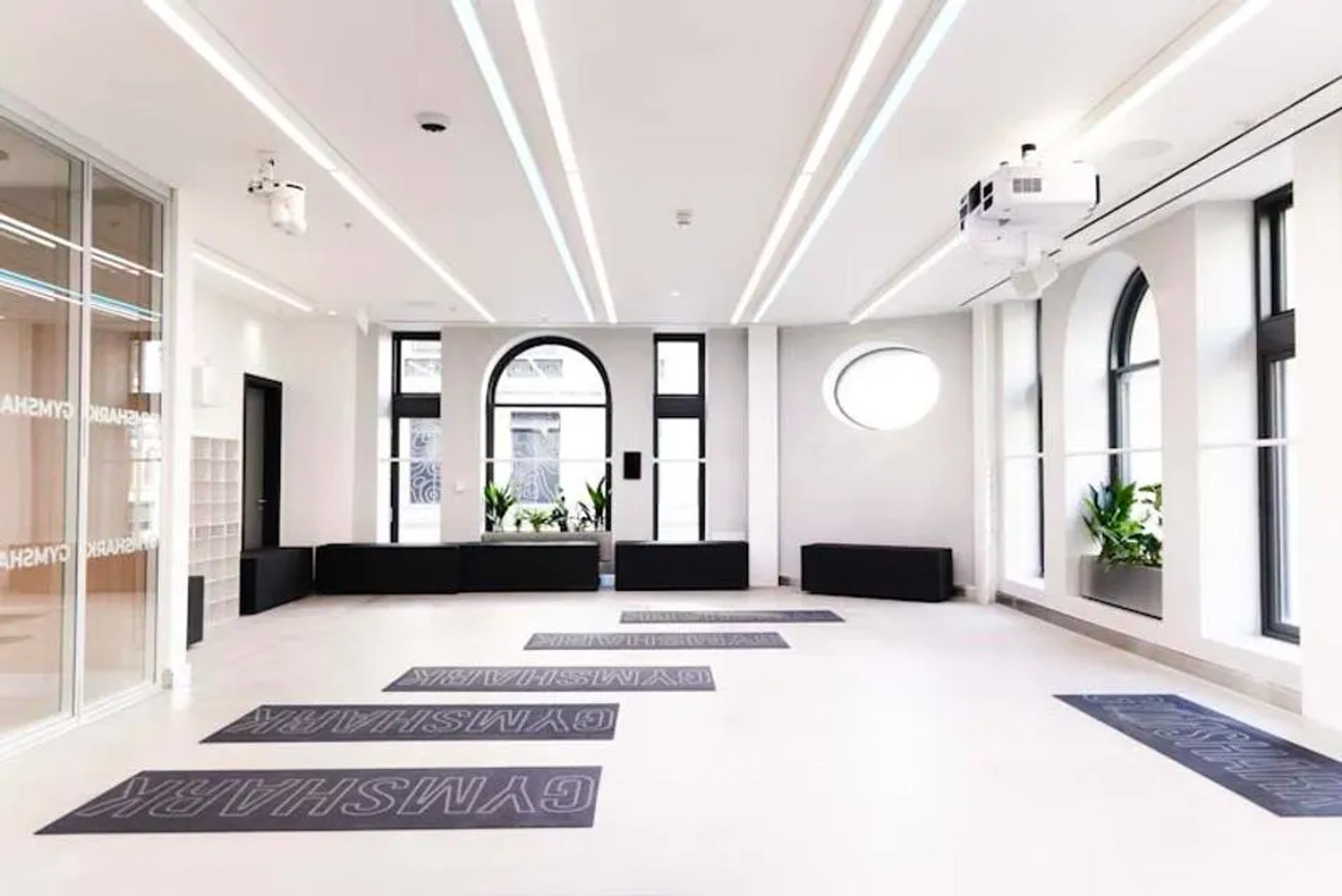 A minimalist store space showcasing black Gymshark mats against clean white walls, providing an inviting environment for mindful movement.