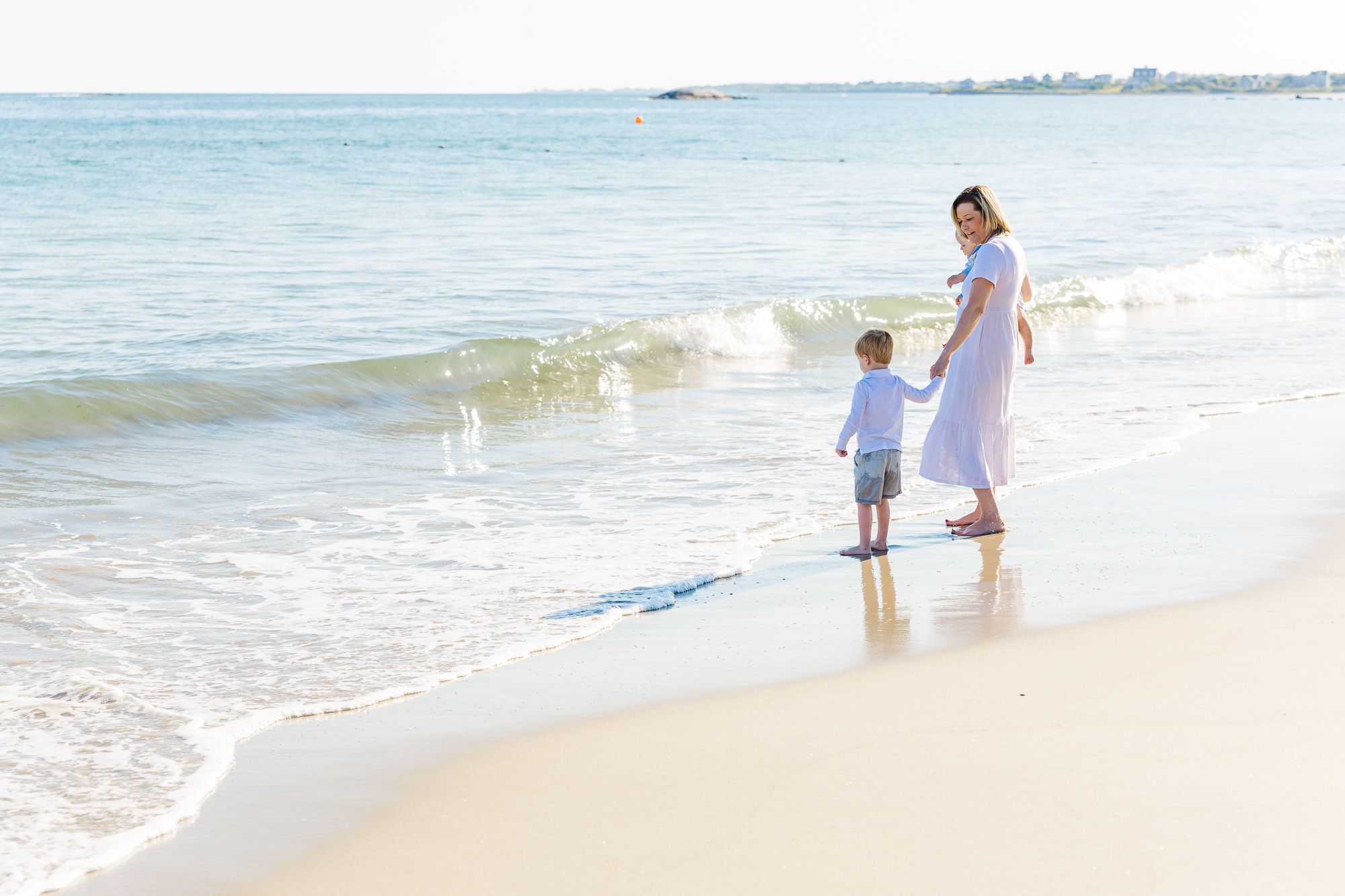 Mother and young children wading in the shallow water at Elephant Rock Beach in Westport, Massachusetts