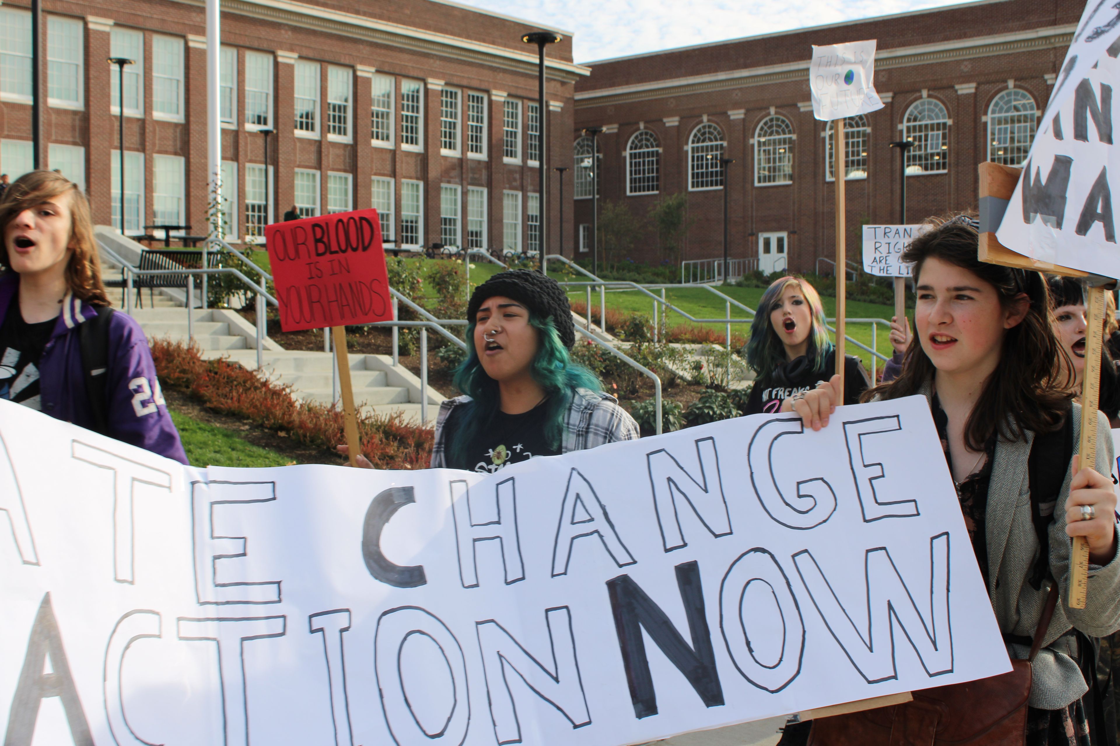 Students hold a banner that says "Climate Chance Action Now" in front of Benson.