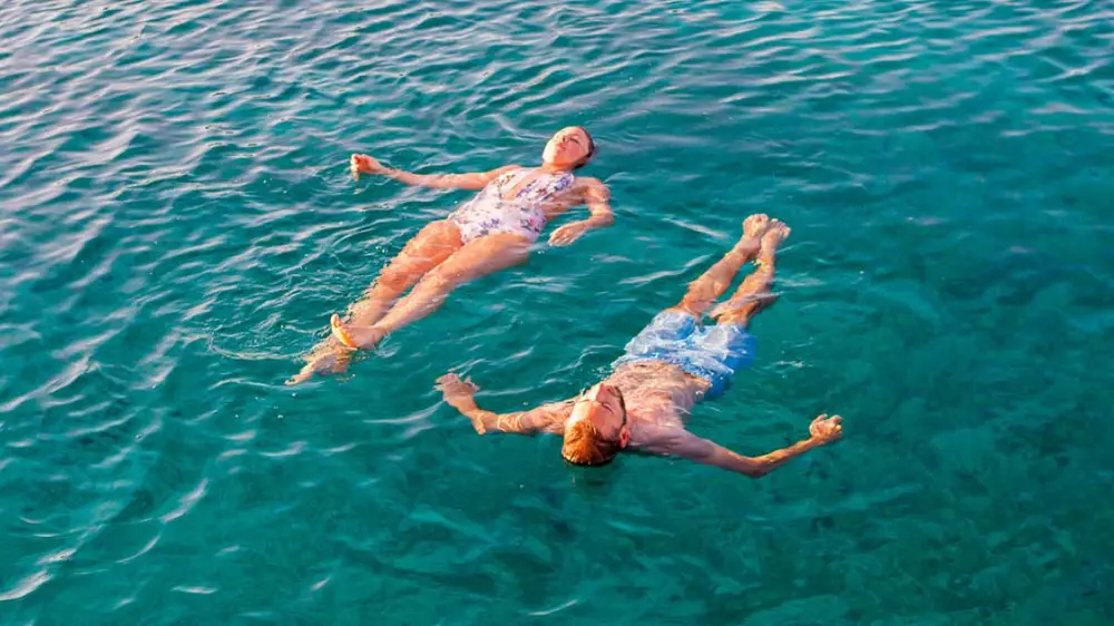 People floating and swimming in turquoise waters around the Croatian islands during their luxury sailing holiday in Croatia.
