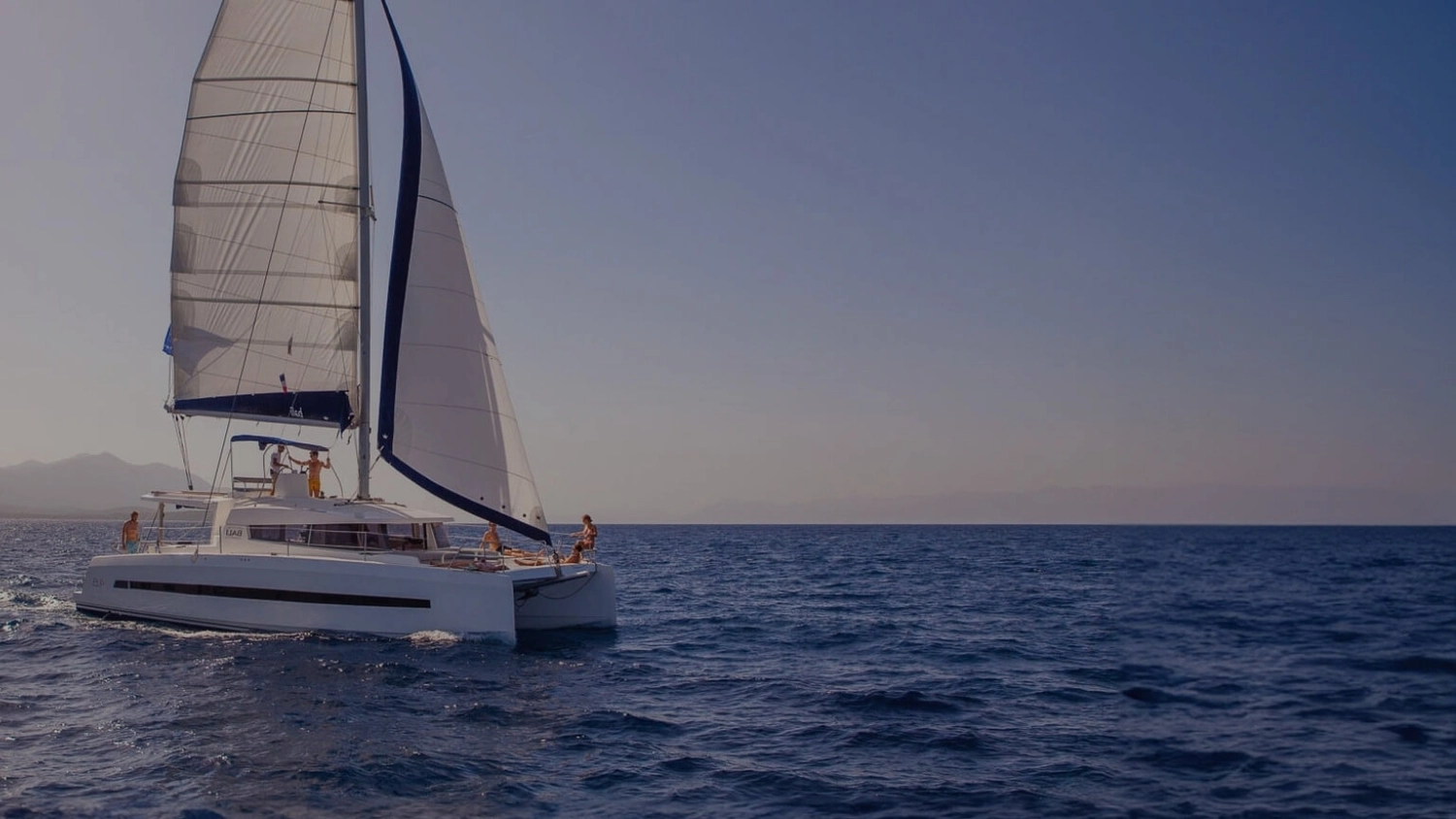 A small group enjoying sunshine and sea views while relaxing on a luxury catamaran sailing holiday in the Mediterranean.