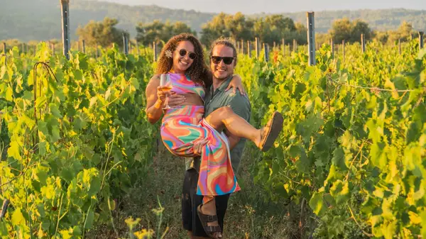 Man holding a woman in his arms in the vines of a vineyard