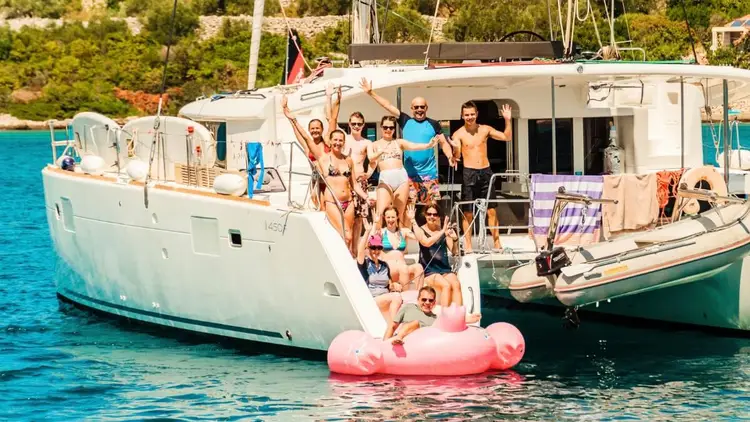 Group of friends enjoying a private catamaran charter in Greece, swimming and relaxing together with Yacht Getaways.