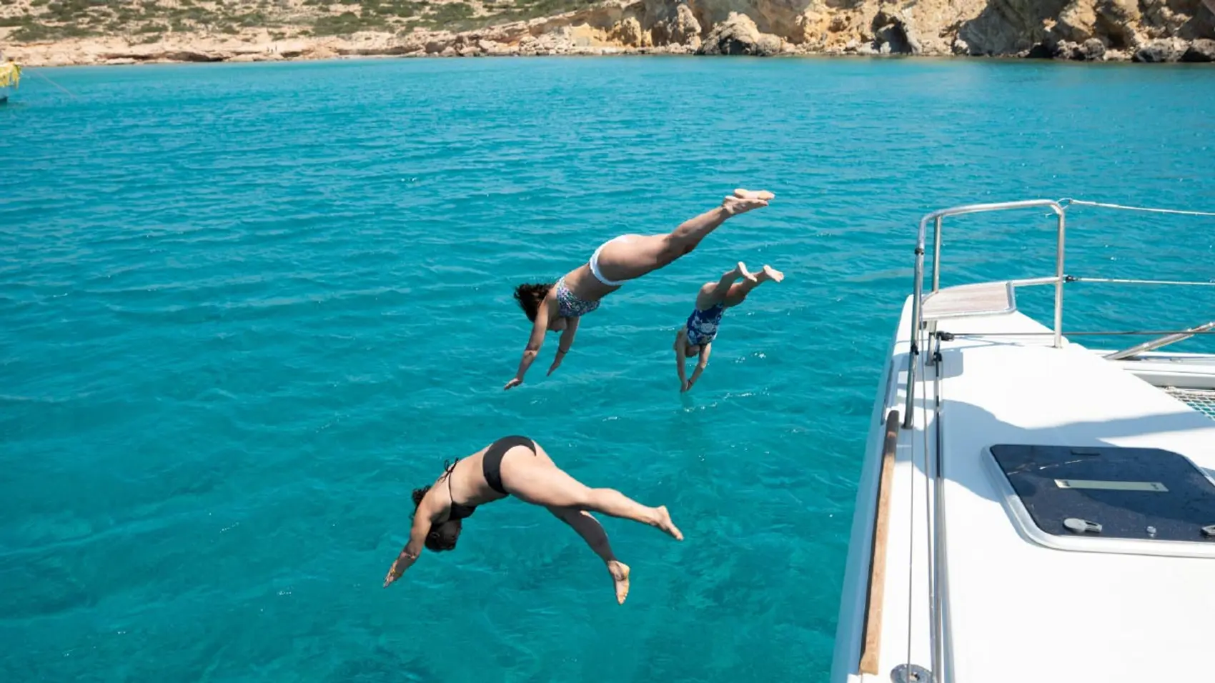 Three women dive off a catamaran into the water in Croatia