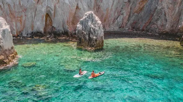 Two people on paddle boards in a bay in Antiparos