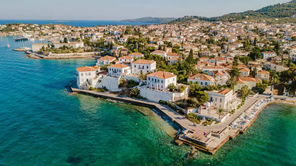 Aerial view of a picturesque Saronic Gulf island town of Spetses surrounded by clear turquoise water on a Greek island-hopping sailing holiday from Athens.