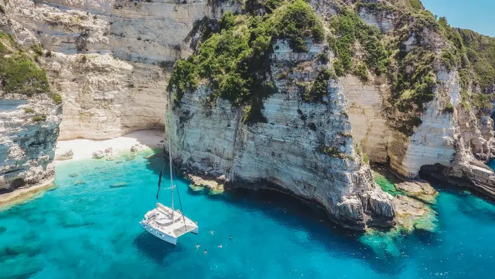 Catamaran anchored in clear water bay in Antipaxos