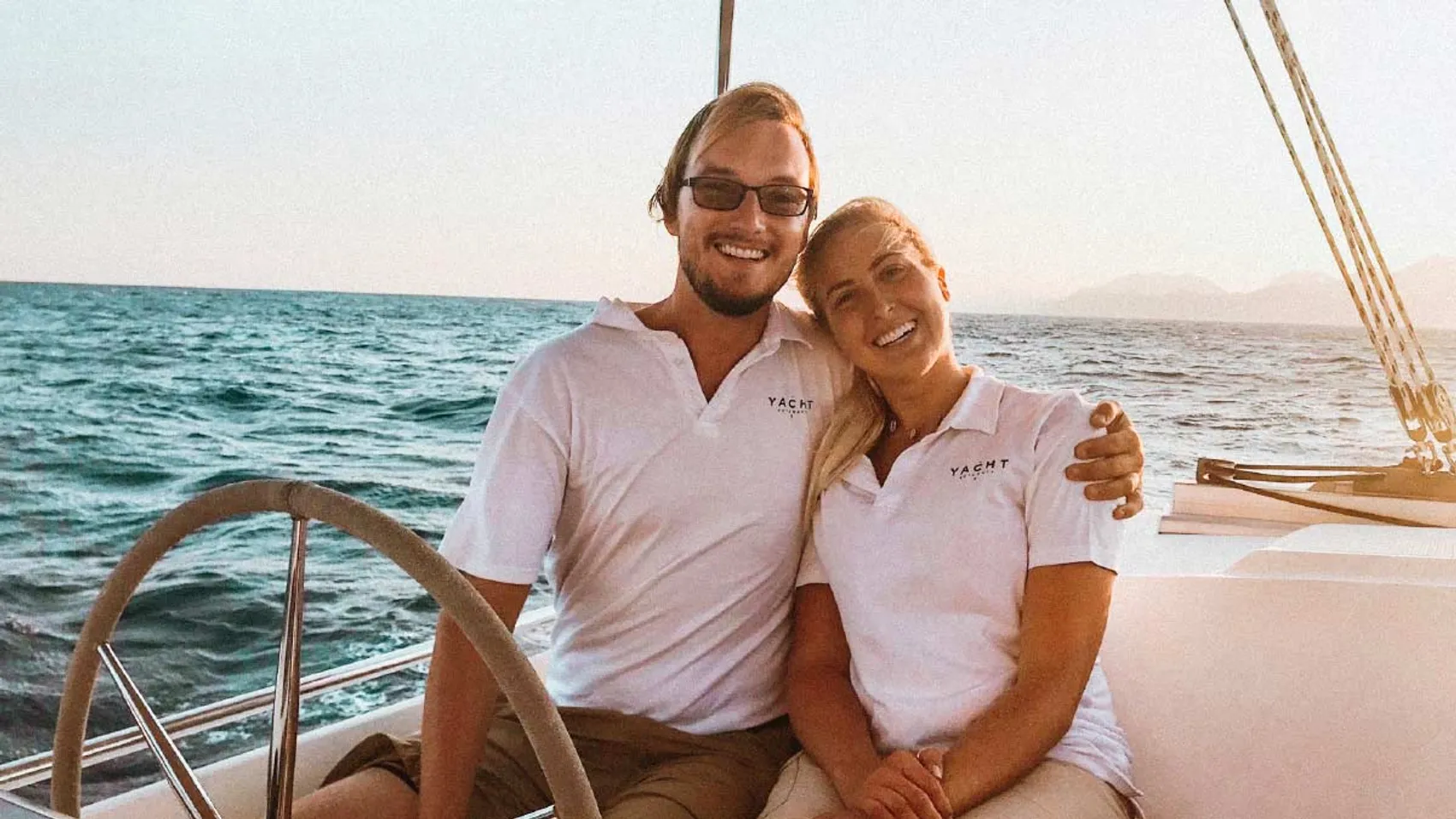 Yacht Getaways skipper and host sitting together at the helm of a catamaran