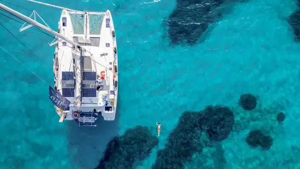 Drone shot of a woman swimming next to a catamaran