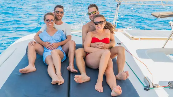 Two couples pose for a photo on a catamaran