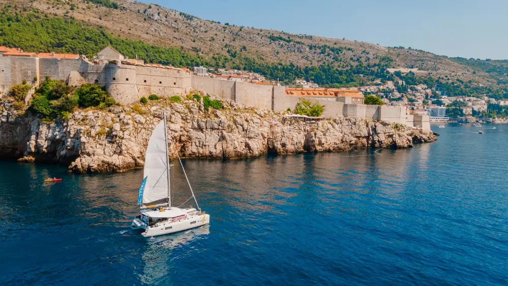 Catamaran sailing in front of Dubrovnik Old Town walls in Croatia