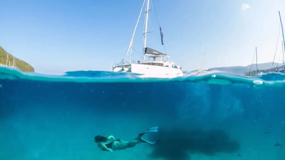 A woman swims and snorkels underwater in crystal clear bays in the Ionian islands of Greece while on a luxury catamaran cruise.