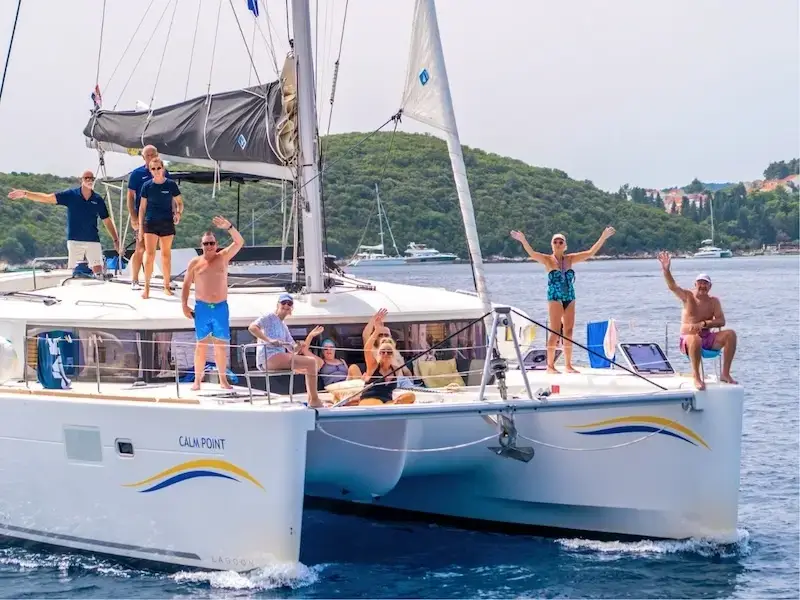 Group photo of a family aboard a luxury catamaran cruise vacation waving and smiling as they sail Croatia with Yacht Getaways.