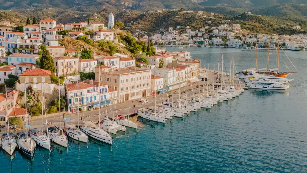 Sailing yachts and catamarans moored along the waterfront in Poros, a colourful Saronic Gulf island visited on Greek sailing holidays from Athens.