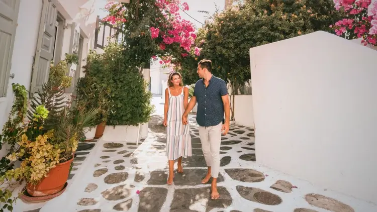 Couple exploring the whitewashed streets of a Greek island together during a Yacht Getaways sailing holiday.