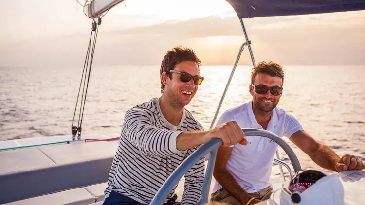 Yacht skipper teaching a guest how to sail