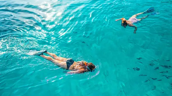 Two people snorkelling in clear blue water