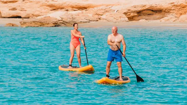 Two people paddle boarding in Greece