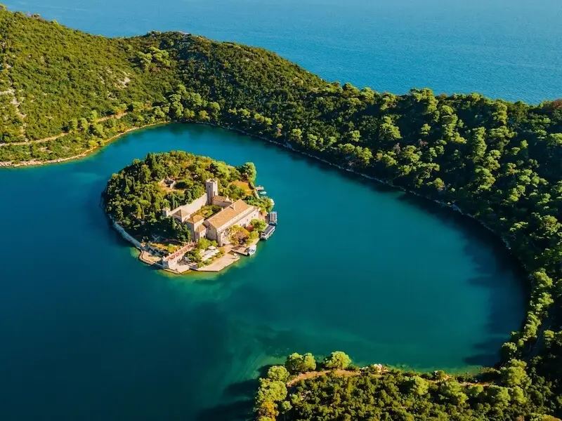 Aerial view of the Benedictine monastery on St Mary’s Island in Mljet National Park, Croatia, surrounded by emerald lakes and forest — a peaceful luxury nature escape on a catamaran cruise with Yacht Getaways.
