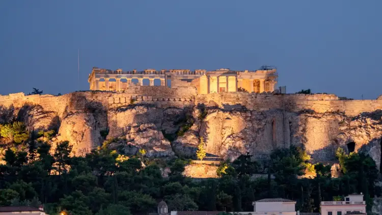 The Acropolis and Parthenon illuminated at dusk above Athens, Greece, with the ancient hill glowing against the evening sky. A strong image for an Athens, Greece travel guide covering the best places to visit in Athens, historic landmarks, sunset viewpoints, and why the city is worth visiting before a wider Mediterranean or Greek islands holiday.