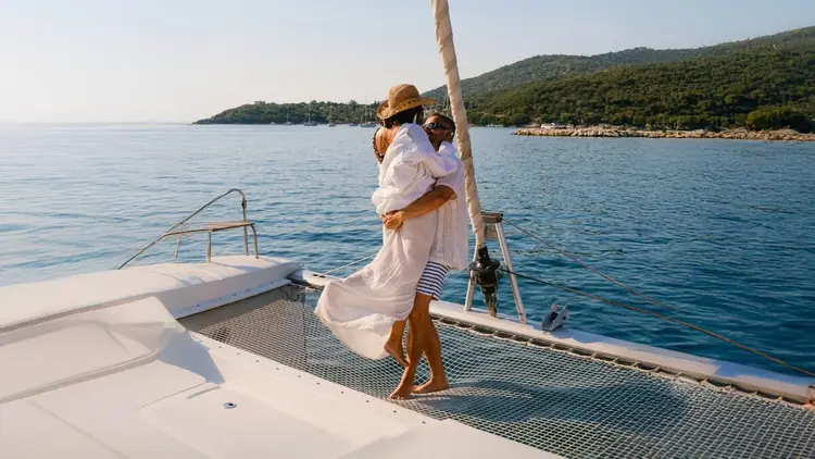 A couple enjoying a private catamaran charter in Greece, swimming and relaxing together with Yacht Getaways.